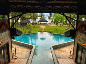 A swimming pool with a view of a beach and palm trees.