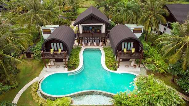 A resort with a central pool, two guest houses, and lush tropical surroundings.
