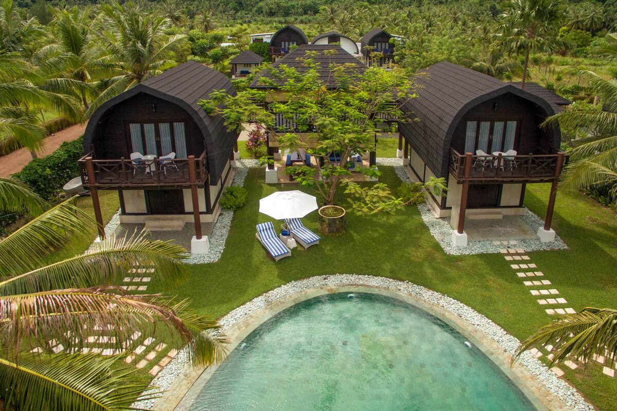 A resort with two large villas, a swimming pool, and lush tropical surroundings.