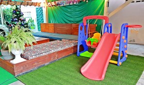A play area with a slide, a bench, and a Christmas tree.