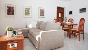 Ein Wohnzimmer mit einer Couch, einem Esstisch mit Stühlen und drei gerahmten abstrakten Bildern an der Wand.