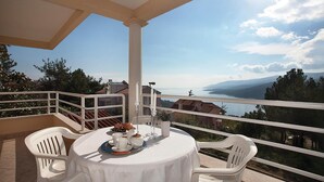 A balcony with a table set for a meal, overlooking a scenic view of a body of water and mountains. - Stunning apartment in Rabac with WiFi (Rabac)