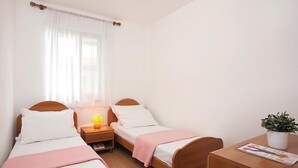 A hotel room with two single beds, a wooden nightstand with a lamp, a small table with a magazine, and a potted plant. - Stunning apartment in Rabac with WiFi (Rabac)