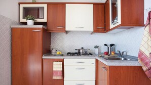A compact kitchen with wooden cabinets, a gas stove, a sink, and a countertop. - Stunning apartment in Rabac with WiFi (Rabac)
