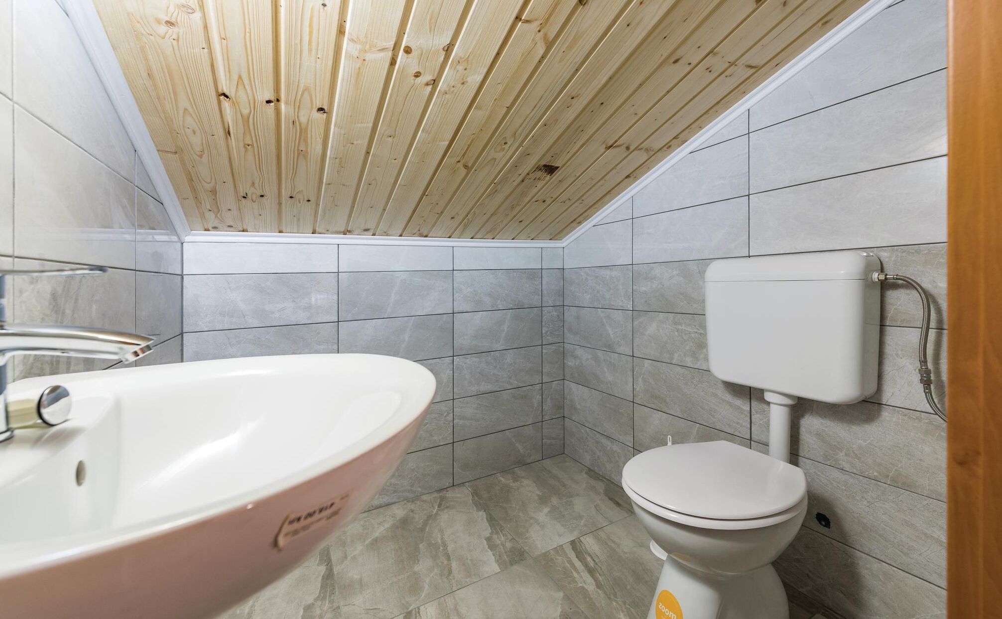 A bathroom with a wooden ceiling, a pink sink, and a toilet.