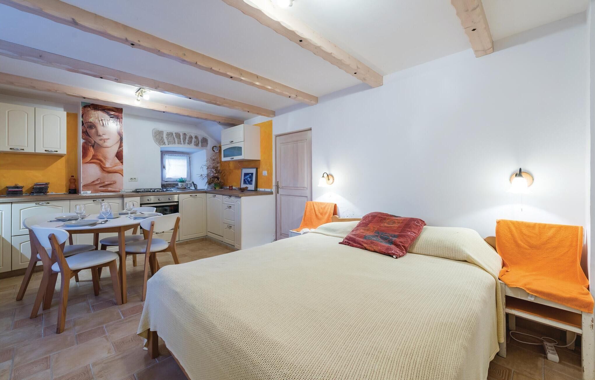 Quarto com cama, mesas de cabeceira e um aparador. Há uma janela com cortinas, uma luminária na parede e uma porta.