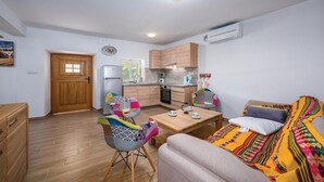 Een ruimtelijke leefruimte met een kitchenette, een eethoek en een bank.