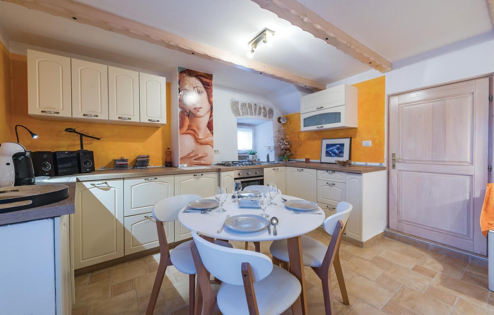 Una cocina con armarios blancos, una mesa de comedor lista para cuatro personas y un cuadro grande en la pared.