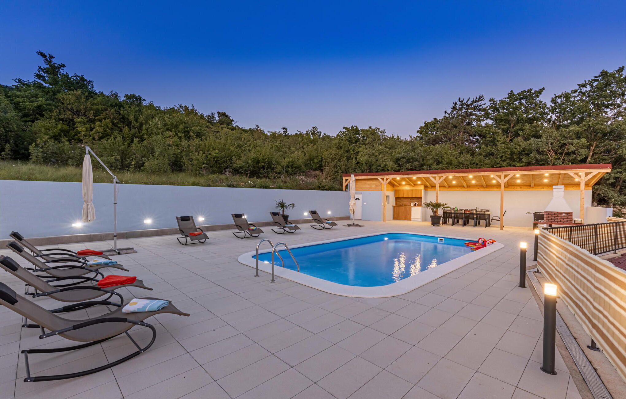 A swimming pool with lounge chairs and a barbecue area.