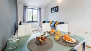 Zona pranzo con tavolo apparecchiato per la colazione, con frutta e succo d'arancia, in una stanza con vista sull'esterno.