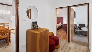 Una habitación con un escritorio de madera, un espejo y una cama con cabecera roja.