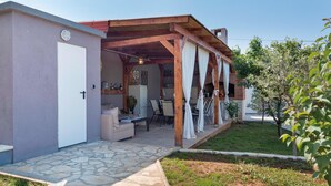 Un espace extérieur aménagé, abrité et doté d’un sol en pierre, d’une cheminée en briques et d’un jardin avec un petit arbre.