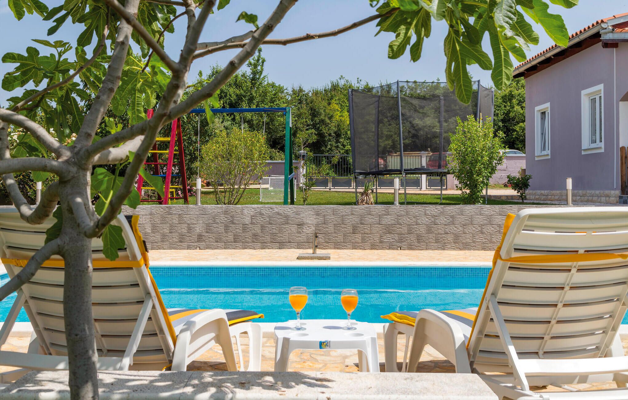 A poolside area with lounge chairs and a table with two glasses of orange juice.