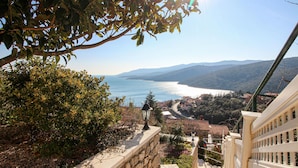 Vista costeira com um caminho de pedra que leva a um edifício com varanda com vista para o mar.