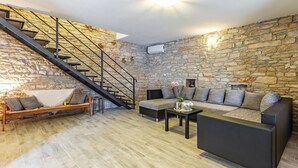 A modern living room with a stone wall, a staircase, a sofa, and a coffee table. - Awesome home in Peruski with WiFi (Peruski)