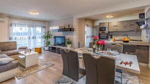 Un appartement moderne comprenant un coin repas, une cuisine, un salon et un balcon agrémenté de rideaux.