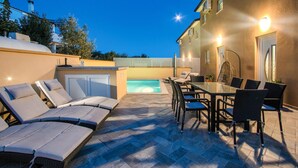 An outdoor patio with lounge chairs, a pool, and a dining area with chairs and a table. - Stunning home in Vodnjan (Vodnjan)