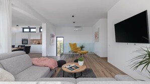 A modern living room with a sofa, a coffee table, and a TV mounted on the wall. - Luxurious home in Pula (Pula)