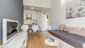 A modern apartment with a dining area, kitchenette, and a living room with a sofa and cushions. - 1 bedroom beach front apartment in Porec (Porec)