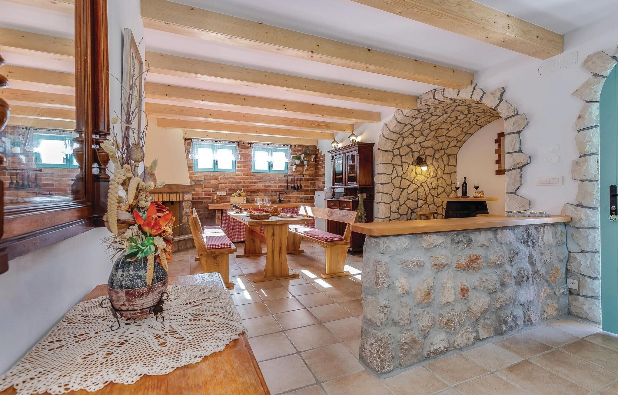 Un intérieur rustique avec des poutres apparentes, une cheminée en pierre et un coin salon confortable.
