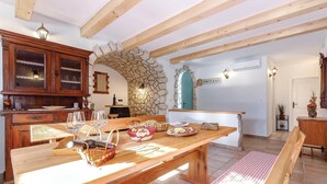 Un comedor con mesa de madera, arco de piedra y vista a una cocina.