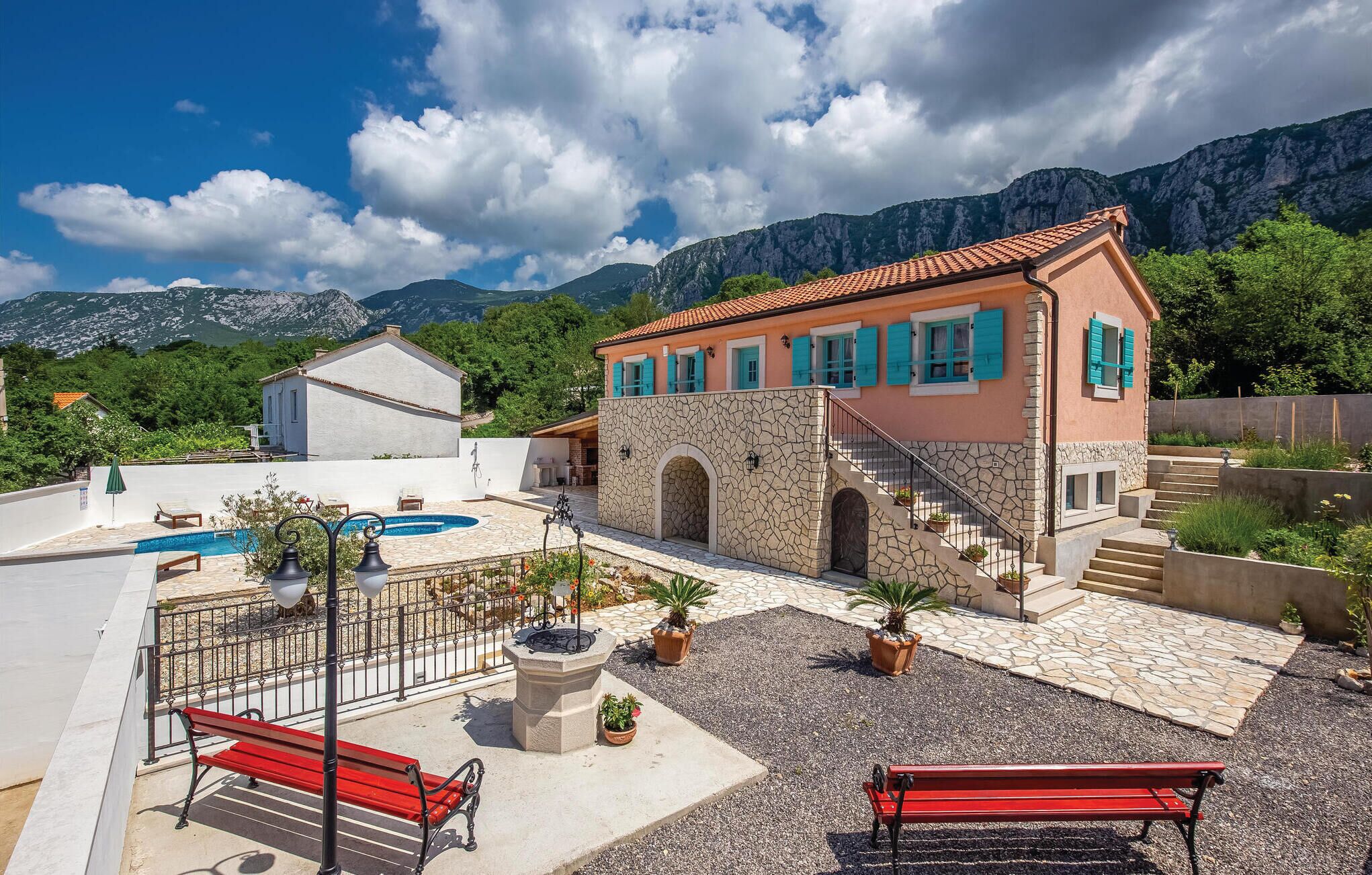 A villa with a swimming pool, outdoor seating, and a view of mountains.