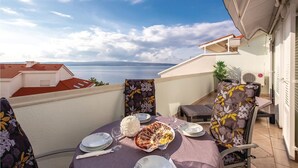 A balcony with a table set for two, overlooking a body of water and a distant coastline. - 2 bedroom pet friendly apartment in Selce (Selce)