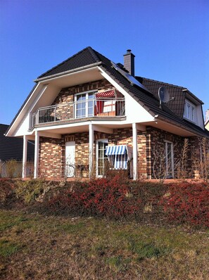 A two-story house with a balcony, brick exterior, and a satellite dish. - Apartment EC - House beach runner (Dranske)