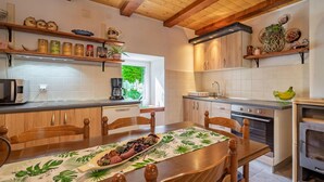 Een moderne keuken met houten kastjes, een inbouwoven en een eethoek met een tafel gedekt voor twee personen.