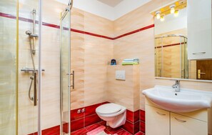 Een badkamer met een douchecabine van glas, een wit toilet en een wastafel met een spiegel erboven.