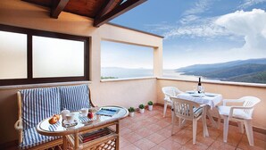 A balcony with a wicker chair, a small table with a tray of food, and a view of the sea and mountains. - Awesome apartment in Rabac with WiFi (Rabac)