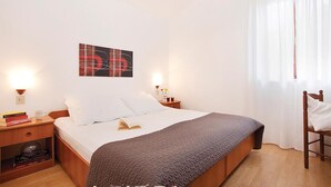 A neatly arranged hotel room with a bed, bedside tables, a wall-mounted artwork, and a window with sheer curtains. - Awesome apartment in Rabac with WiFi (Rabac)