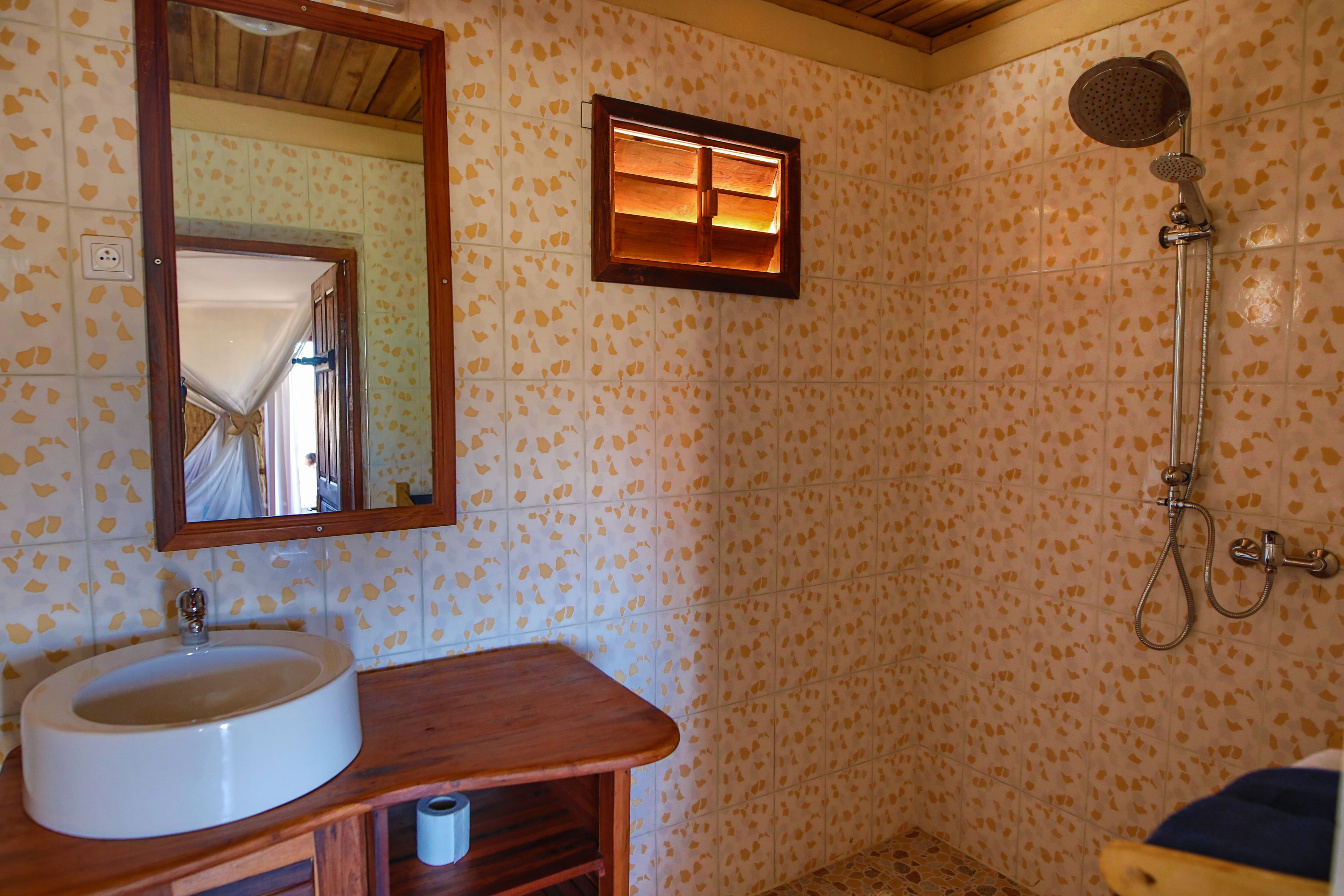 A bathroom with a sink, mirror, shower, and patterned tiles.