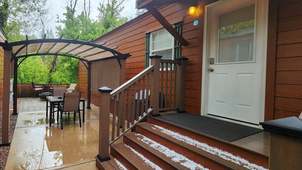 A wooden deck with a covered patio area, a door, and steps leading to a covered porch.