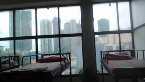 Una habitación con literas y amplias ventanas con vistas a un paisaje urbano.
