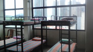 Un dormitorio con literas, una silla y una ventana con vistas a la ciudad.