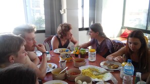 Un grupo de personas cenando en una mesa con diversos platos y bebidas.