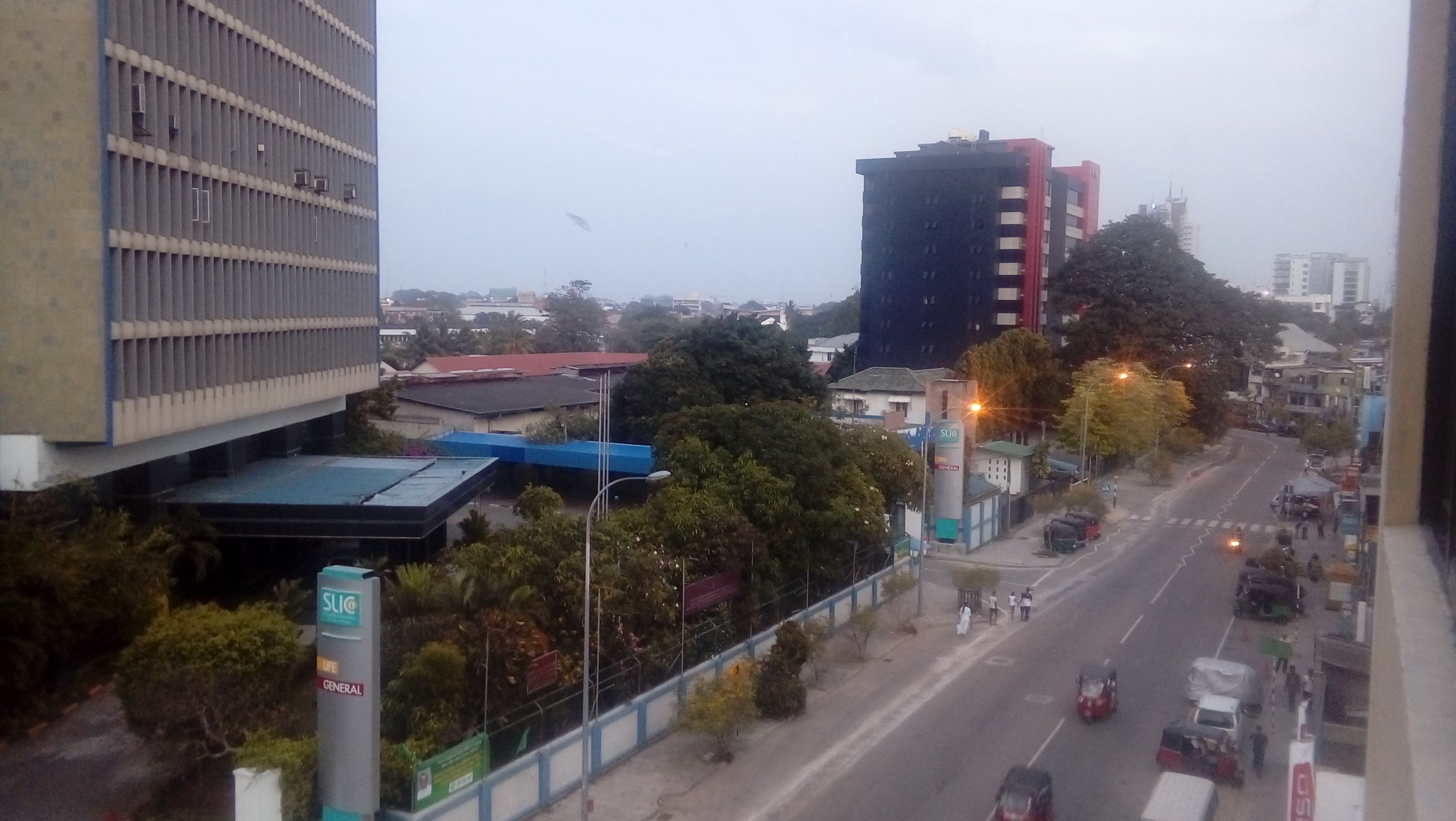 A city street with buildings, trees, and vehicles.