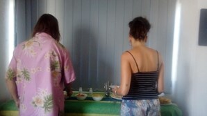 Dos personas de pie en una habitación con una mesa frente a ellas.