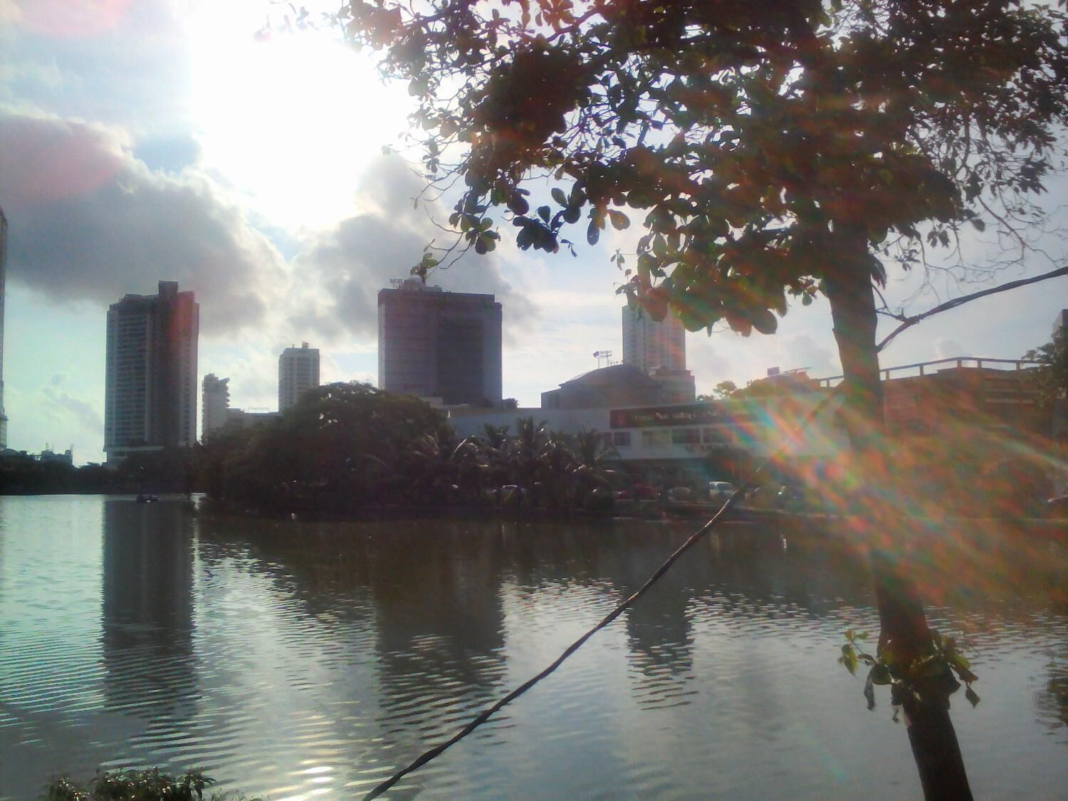Un paisaje urbano con edificios altos y una masa de agua que refleja el horizonte.