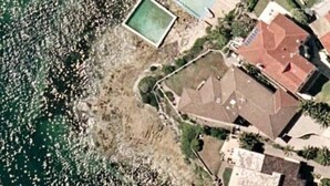 An aerial view of a coastal property with a swimming pool, a fenced garden, and a house with a red roof. - Waterfront on Manly Harbour (Manly)