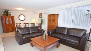 A living room with two leather sofas, a wooden coffee table, and a cabinet. - Waterfront on Manly Harbour (Manly)