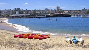 A beach with kayaks and a pier in the background. - 713 at the Beach (Manly)