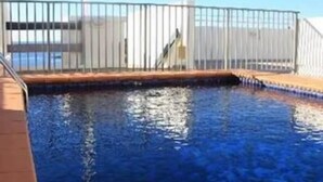 A swimming pool with a metal railing, a clear sky, and a distant view of a building. - 713 at the Beach (Manly)