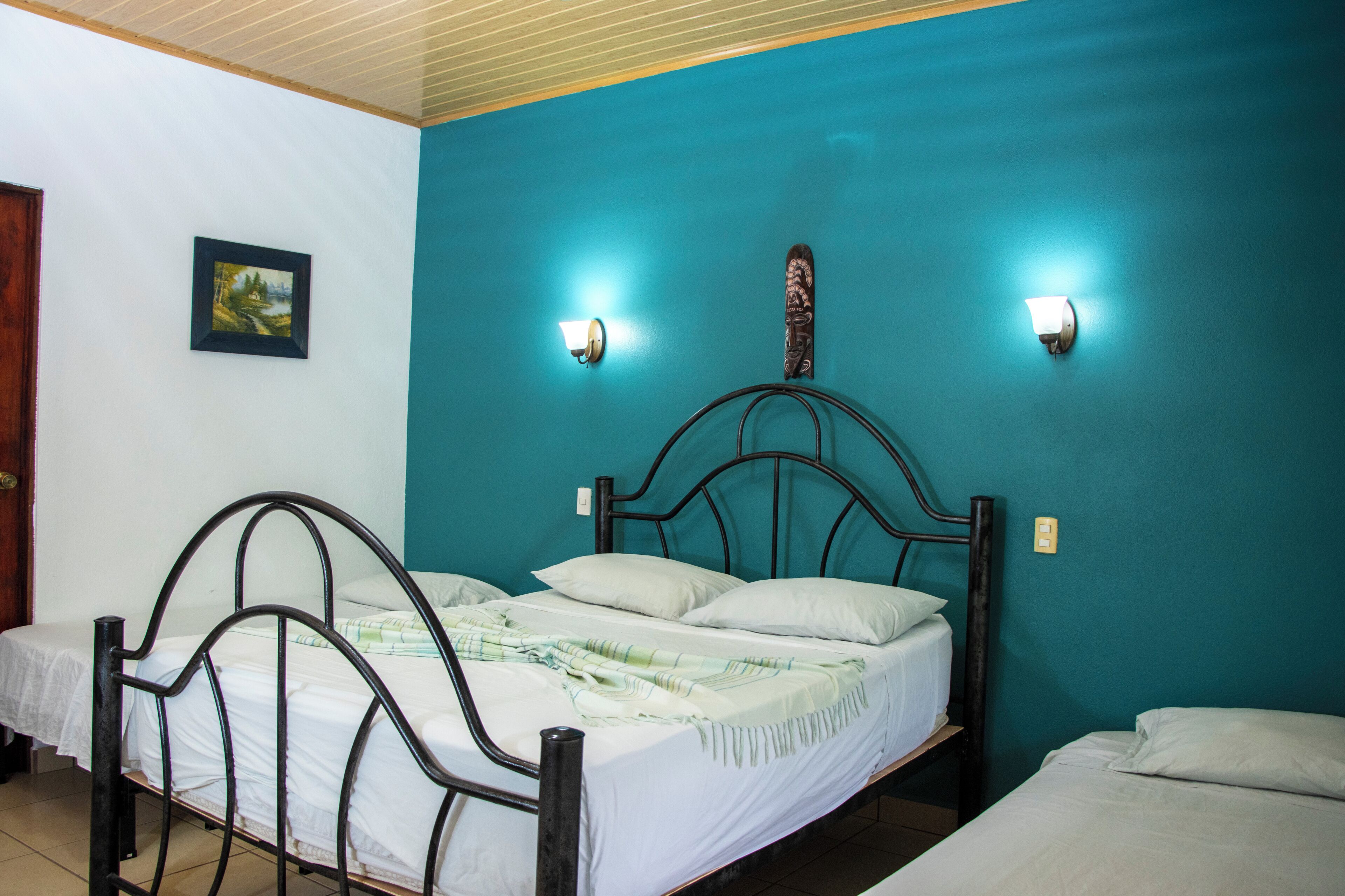 A room with a bed, a bedside table, a wall-mounted light, and a framed picture.