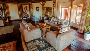 A cozy living room with a sofa set, a coffee table, and a blue chair. - Ingagi Park View Lodge (Kinigi)