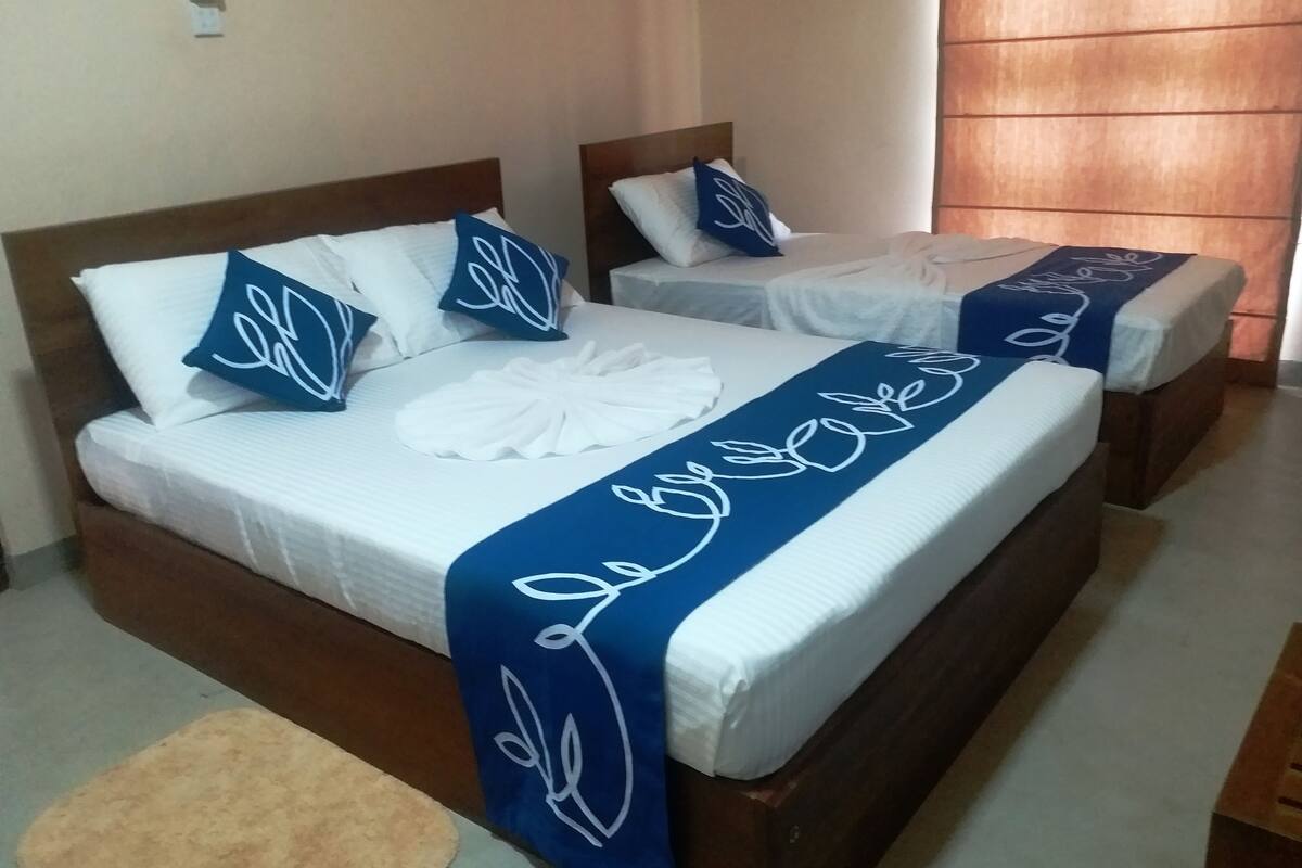 Una habitació d'hotel amb dos llits, cada un amb roba de llit blanca i nínolls decoratius blaus.