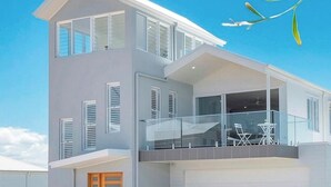A modern two-story house with a balcony, large windows, and a garage.