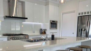 A modern kitchen with stainless steel appliances, a central island with bar stools, and a built-in oven.