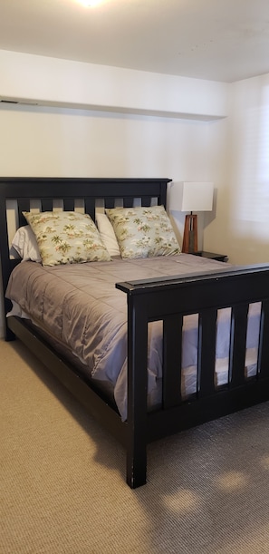 A bed with a dark wooden frame, a beige mattress, and floral-patterned pillows.